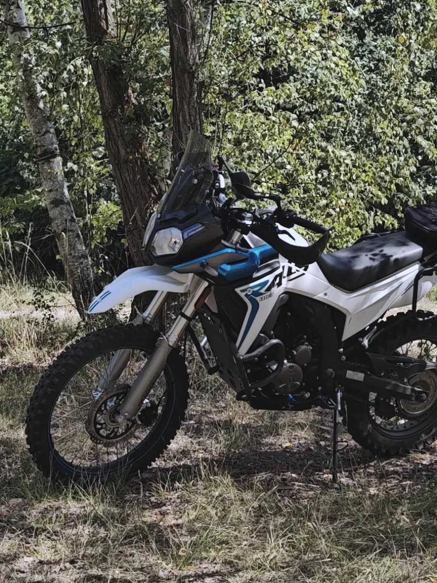 Voge 300 Rally in white-blue on a forest track